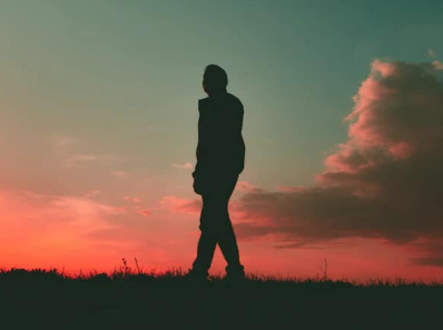 a silhouette of a man walking on the grass